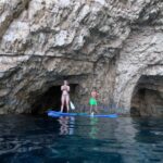 A Couple coming out from a cave with a SUP