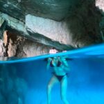 a girl dives into an underwater cave