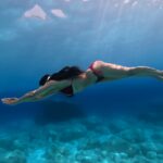 a girl dives in super blue water